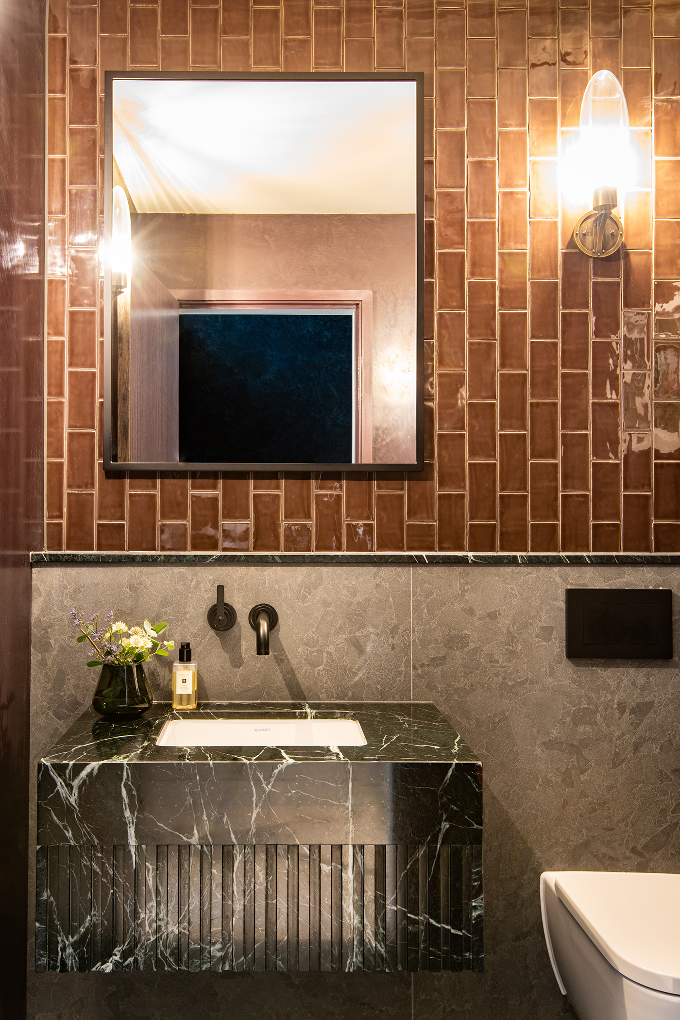 Powder room with brown tiles black stone vanity and Landmark Pure basin mixer by Samuel Heath